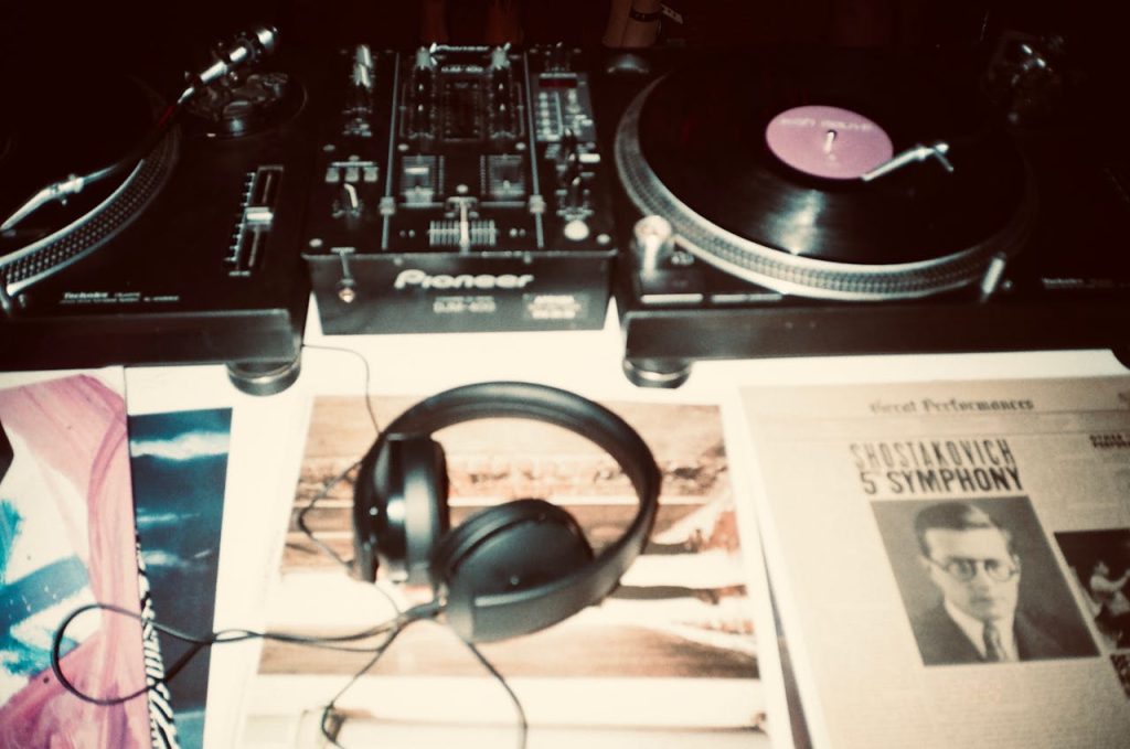 black-corded-headphones-3413462 Close-up of a vintage DJ setup featuring turntables, vinyl records, and headphones, capturing the essence of retro music.