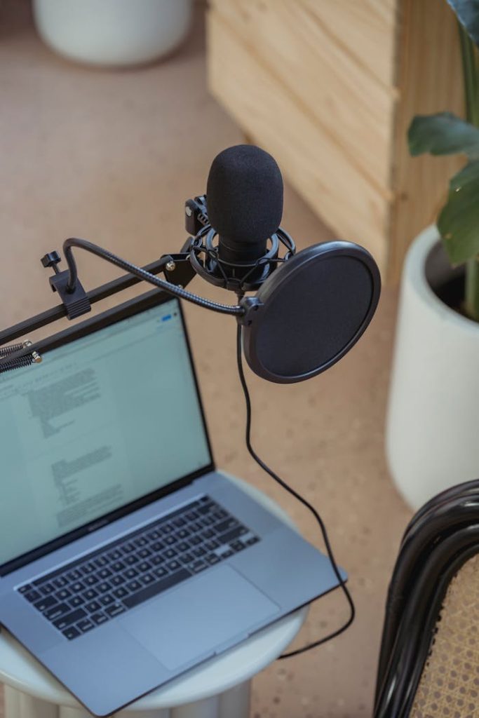 microphone-on-tripod-attached-to-laptop-in-studio-6953871 A modern podcast setup featuring a laptop and studio microphone on a desk, ideal for digital media production.